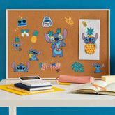 Cork bulletin board with cartoon character stickers on a desk against a blue wall.